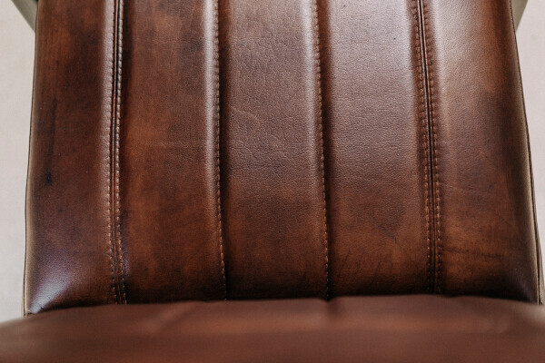 Gros plan sur le rembourrage de l'assise en cuir marron avec coutures décoratives