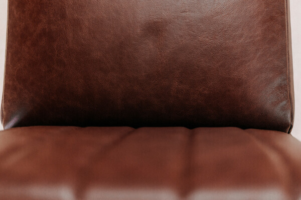 Gros plan sur le rembourrage en cuir marron texturé de la chaise cantilever de salle à manger