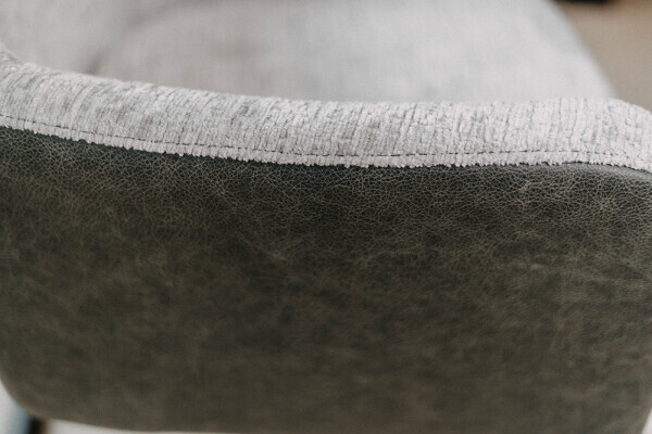 Gros plan sur la couture entre le tissu et le cuir sur la chaise.
